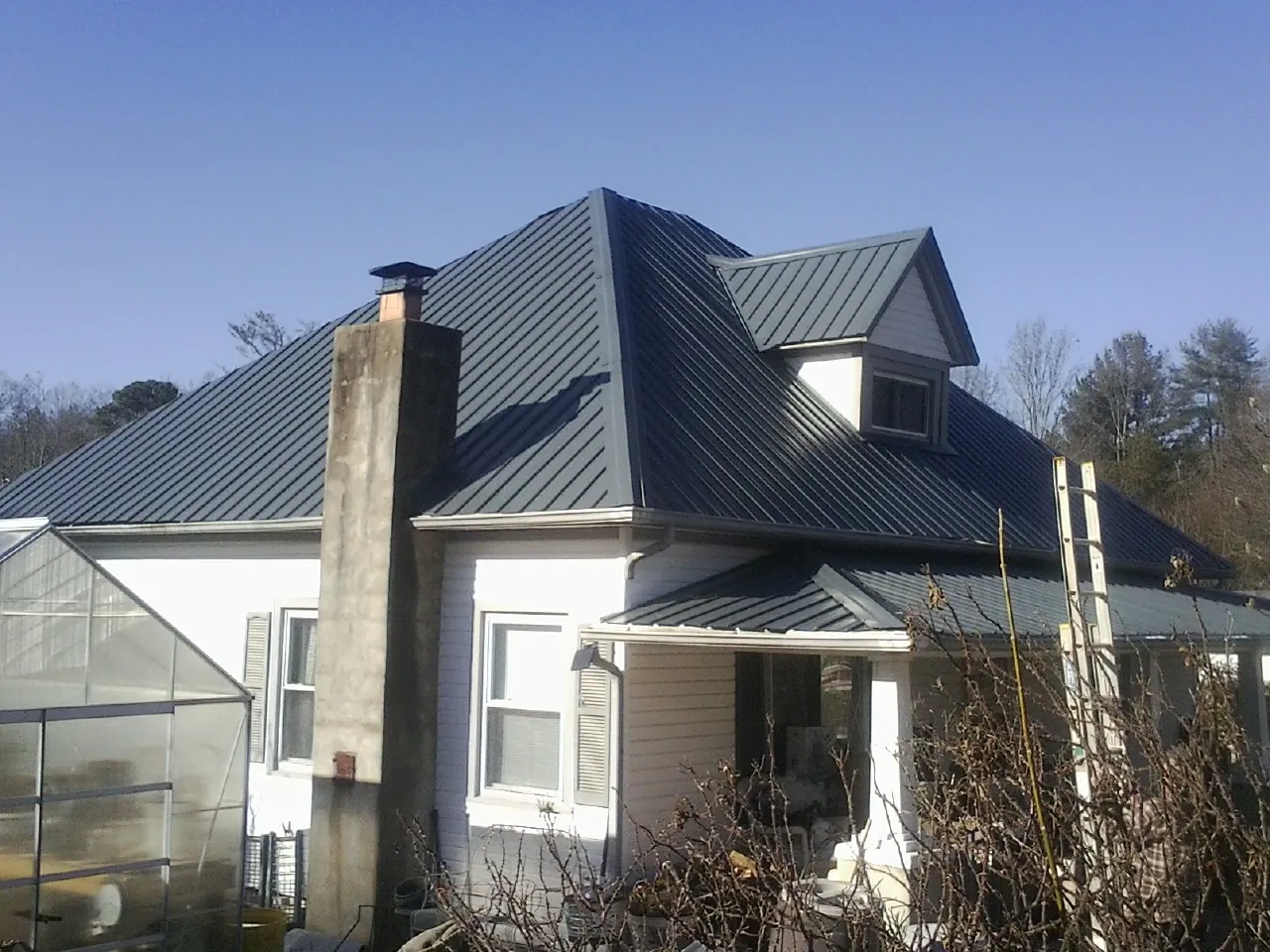 Dark blue standing seam metal roof on a white farmhouse with dormer — Slate & Tile Roof Repair by Roofing Brothers in Pleasant Plains
