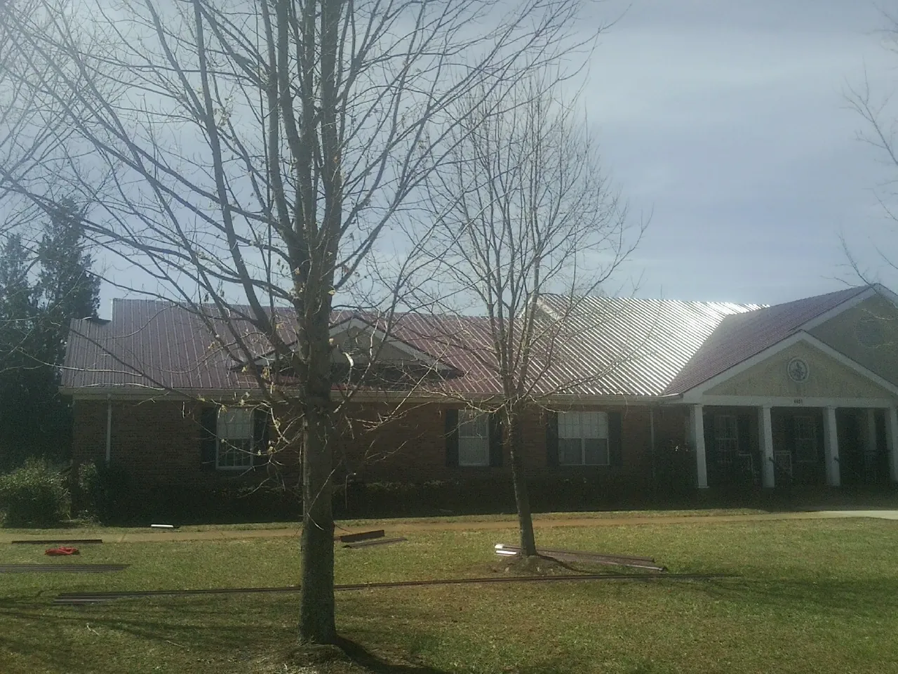 Red metal roof on a brick building seen from the front lawn in Pleasant Plains