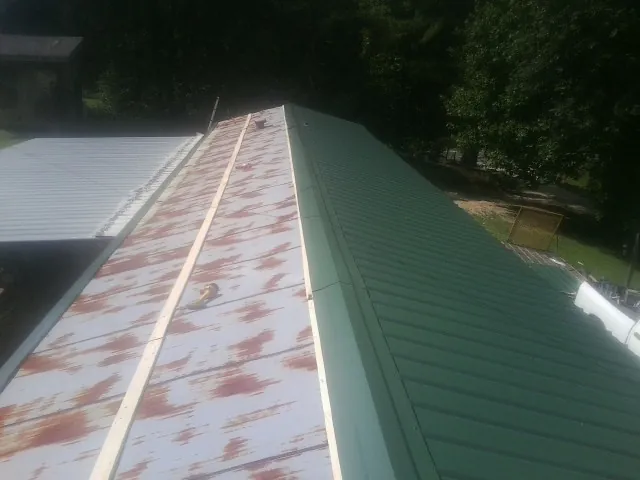 Old rusted panels beside newly installed green metal roofing — Wind Damage Roof Repair by Roofing Brothers in Pleasant Plains