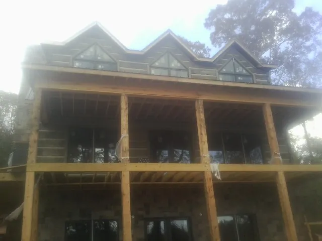 Dormers and porch framing on a large log home under construction — Roof Coating work by our crew in Pleasant Plains