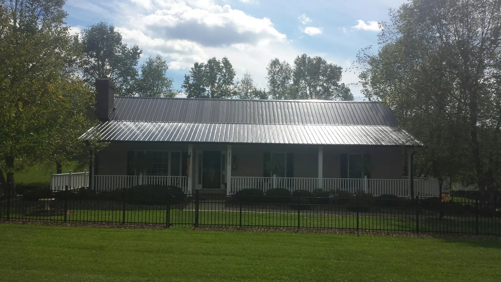 Gray metal roof on a brick ranch with a full width front porch — Gutter Guard Installation work by our crew in Pleasant Plains