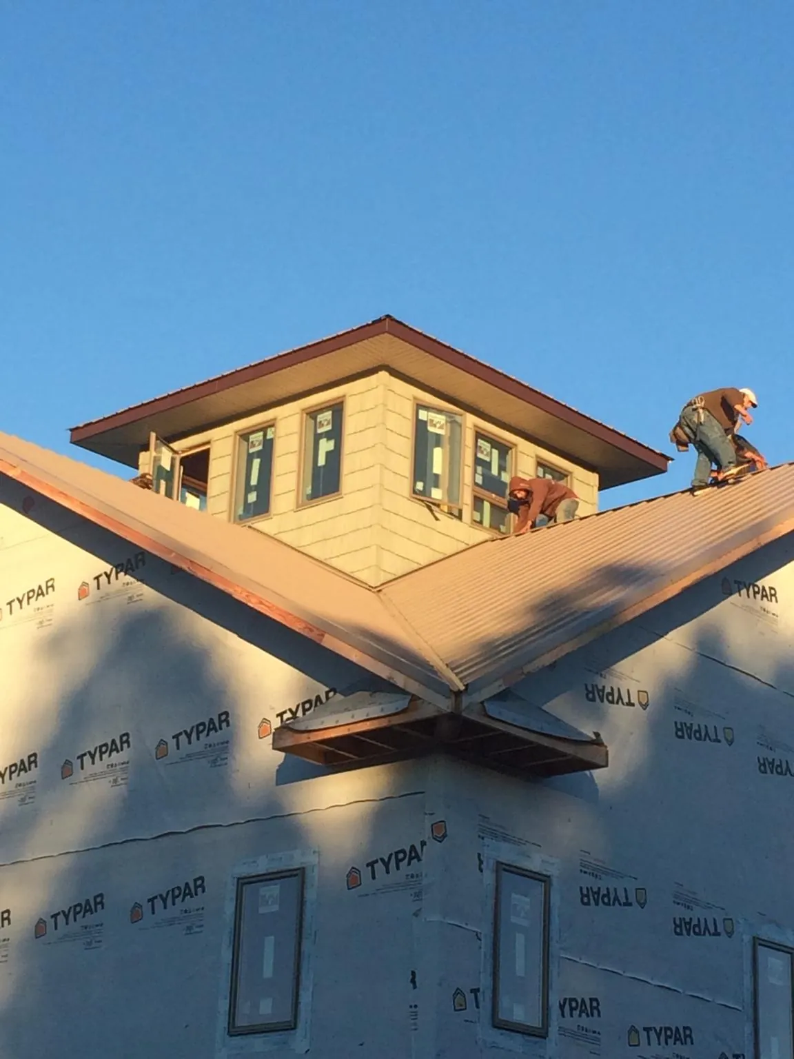 Roofers working around a rooftop cupola on a new metal roof at sunset — Roof Waterproofing in Pleasant Plains by Roofing Brothers